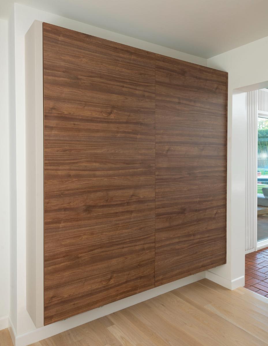 a horizontally grained wood veneer wall-mounted cabinet concealing coffee and beverage bars designed by eggersmann for a Preston Hollow kitchen renovation