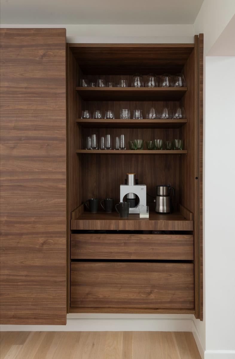 right pocket door open in a horizontally grained wood veneer wall-mounted cabinet to reveal a beverage bar designed by eggersmann for a Preston Hollow kitchen renovation