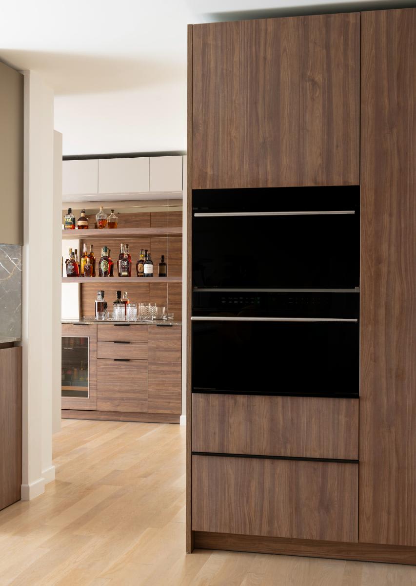 Wolf oven and steam oven at entrance to butler's pantry featuring a modern bar designed by eggersmann for a Preston Hollow kitchen renovation
