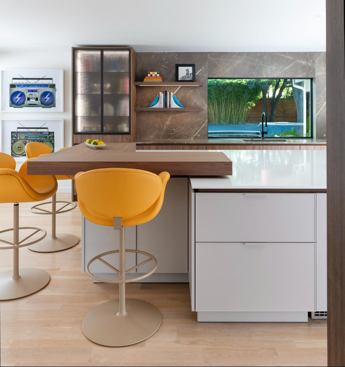 bright modern bar stools bring pops of color into a mid-century white and warm wood kitchen designed by eggersmann dallas for a Preston Hollow kitchen renovation