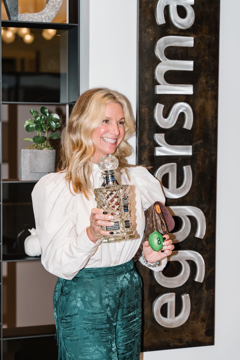 guest poses with a bottle of tequila at a tequla tasting event at the eggersmann laguna showr