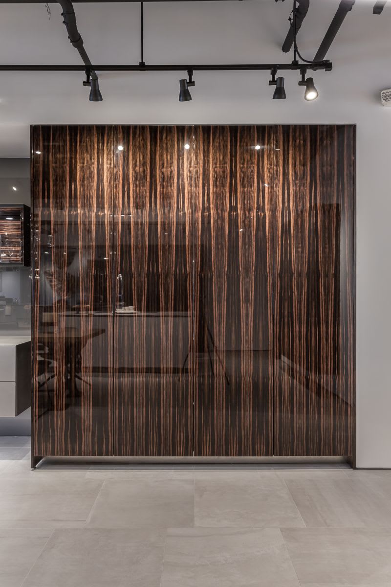 exotic high gloss pocket doors hide a bar area with sink in high gloss vertical macassar veneer