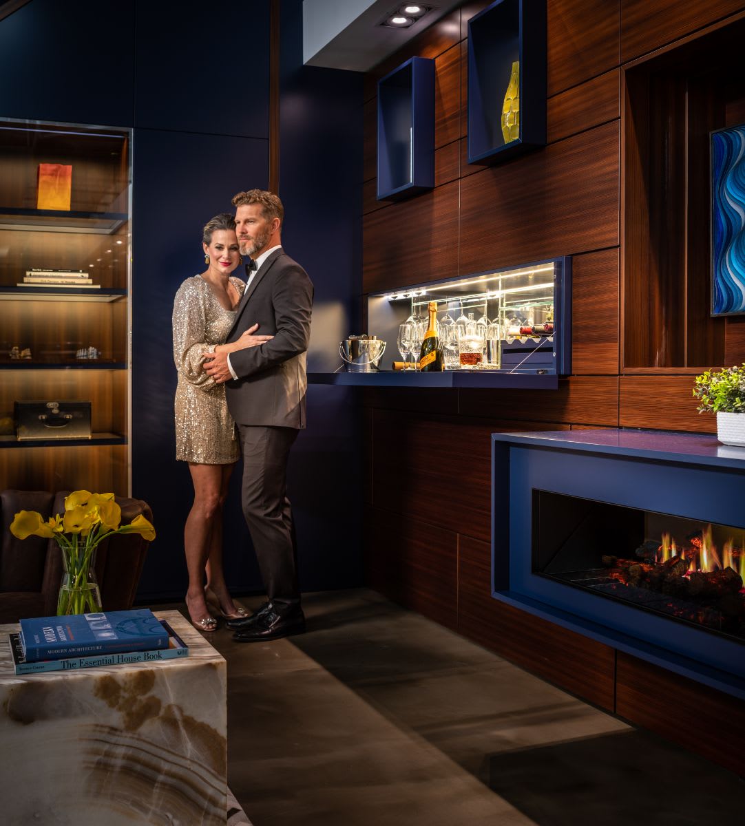 romantic couple beside a fire in a great room featuring a wall-mounted horizontal fireplace by dimplex beside a hidden bar in an eggersmann-designed media wall