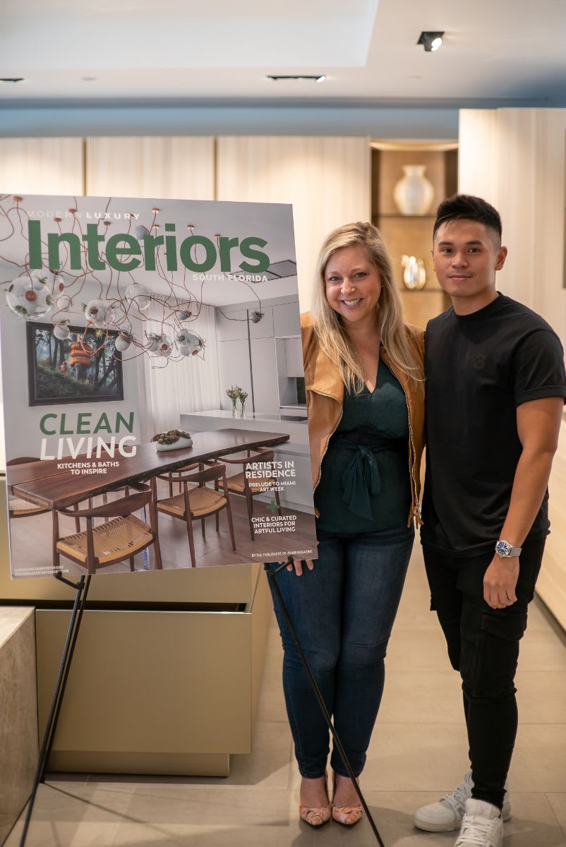 jesse bratter, editor of modern luxury interiors south florida posing with an enlarged MLI magazine cover