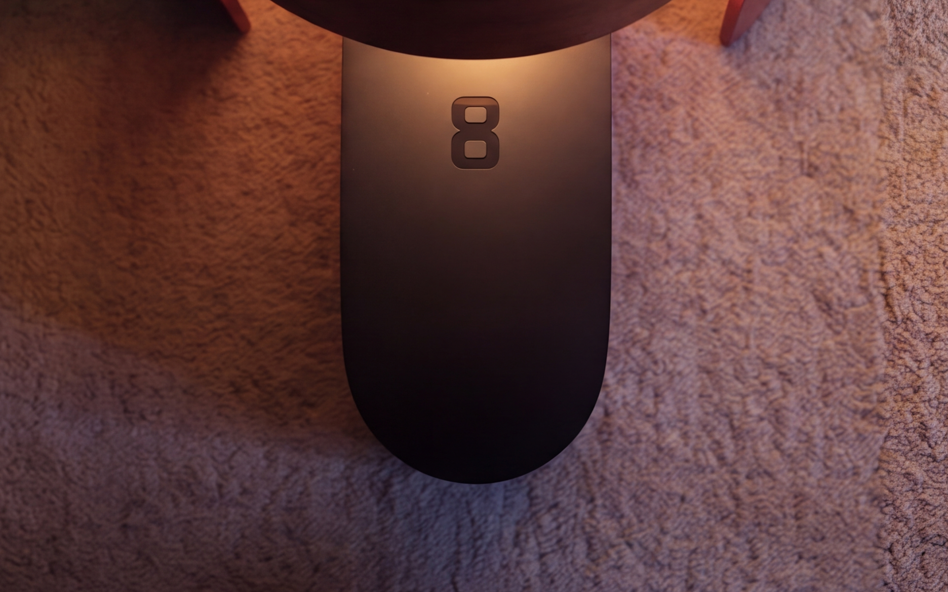 An Eight Sleep Pod beside a bed, its light pooling on the carpet
