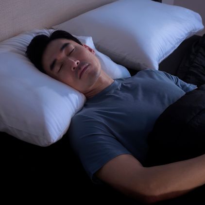 A man asleep on his back with his head resting on a pillow
