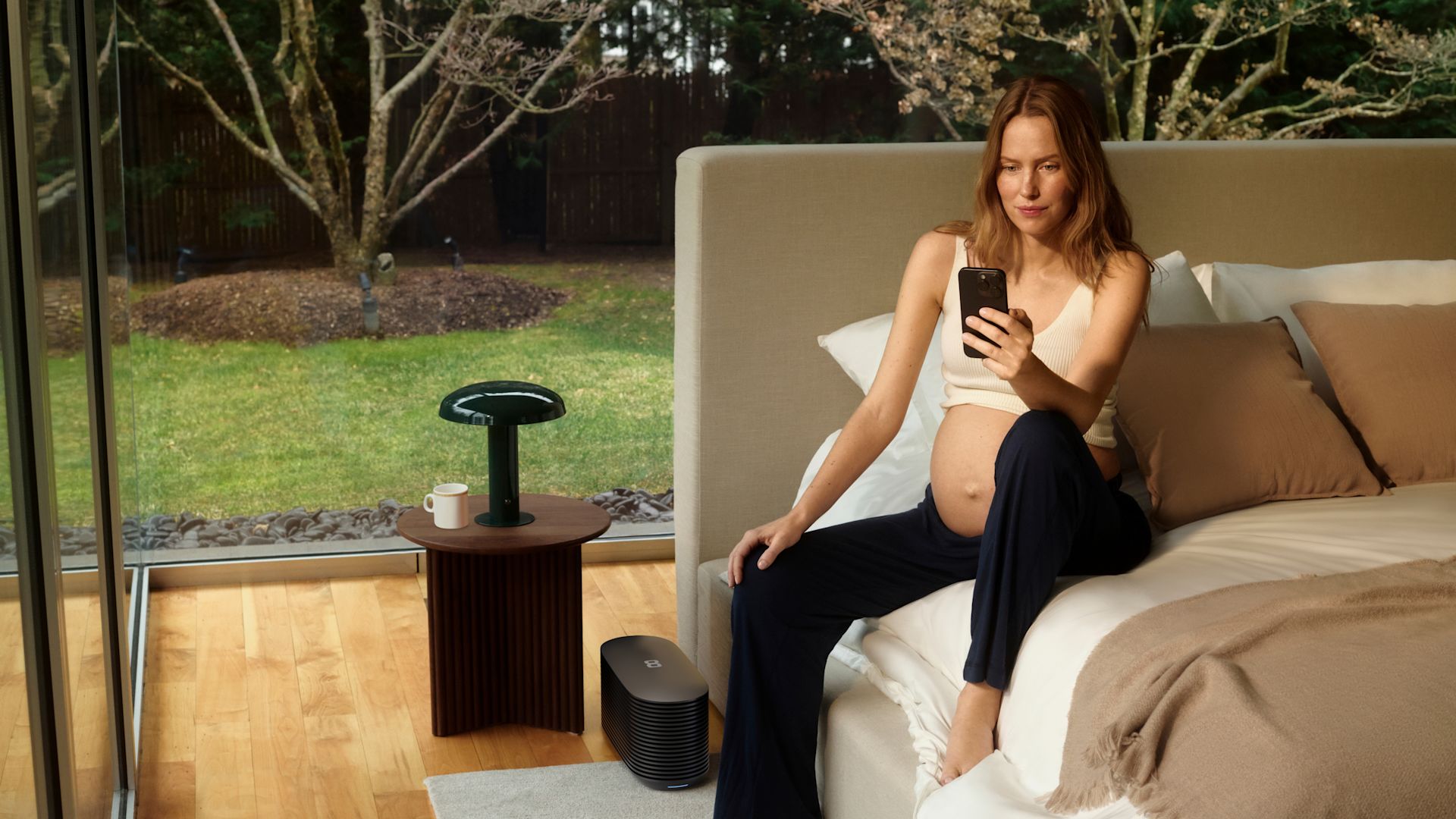 A pregnant woman checking her sleep insights beside the Pod
