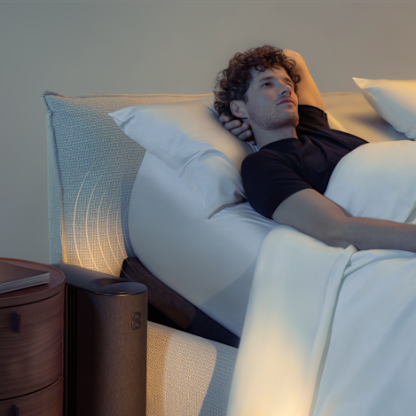A man in bed with the Pod 5 Ultra Base playing a soundscape
