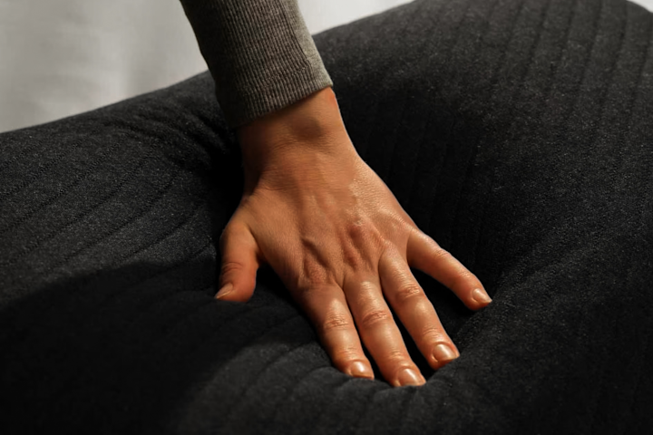 A hand resting on the Pillow Cover quilted surface.