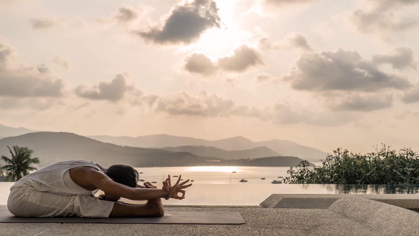 Frau macht Yoga-Vorbeuge am Meer Frau macht Yoga-Vorbeuge am Meer