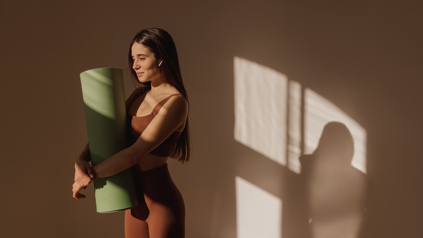 Frau mit Yogamatte im Arm