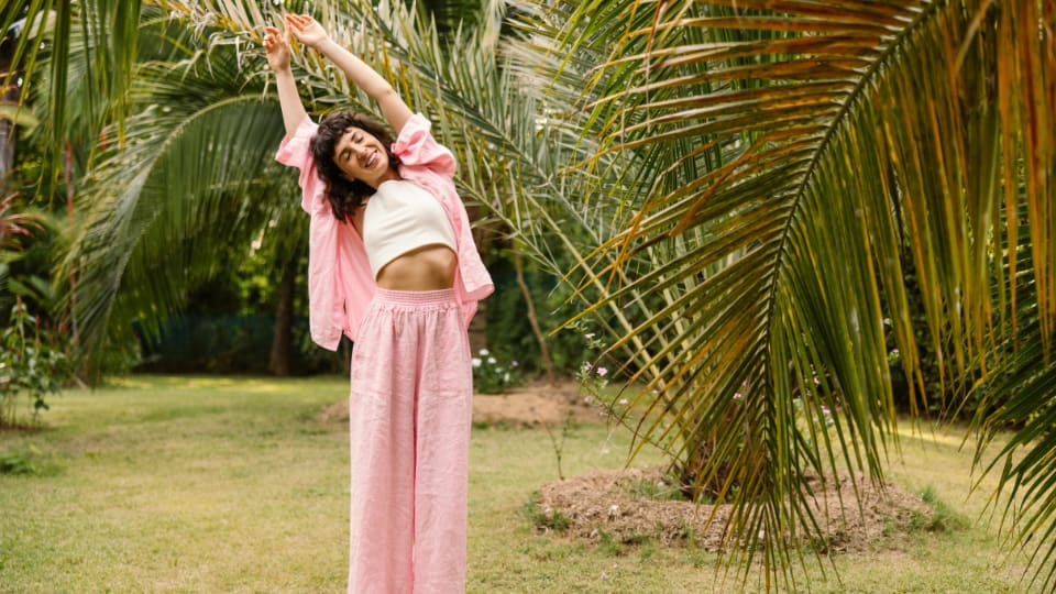 Frau in Dehnhaltung vor Palmen