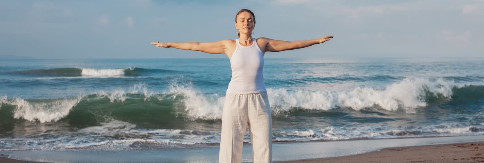 Frau mit ausgestreckten Armen vor Meer | Longevity