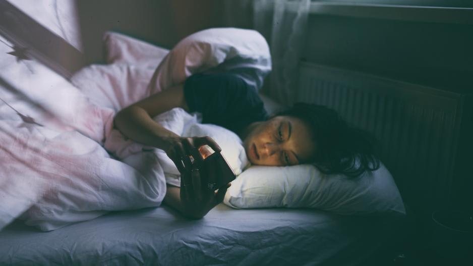Neidische Frau im Bett Frau im Bett schaut neidisch auf ihr Handy