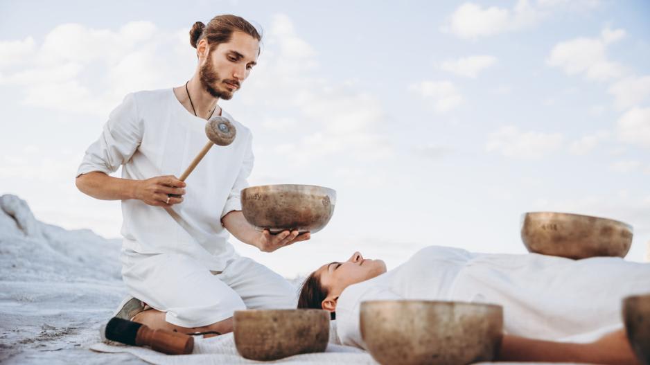 Mann macht Klangschalentherapie mit Gong-Schalen Mann macht Klangschalentherapie mit Gong-Schalen