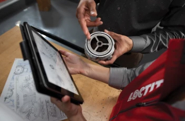 Hands holding an iPad and industrial equipment