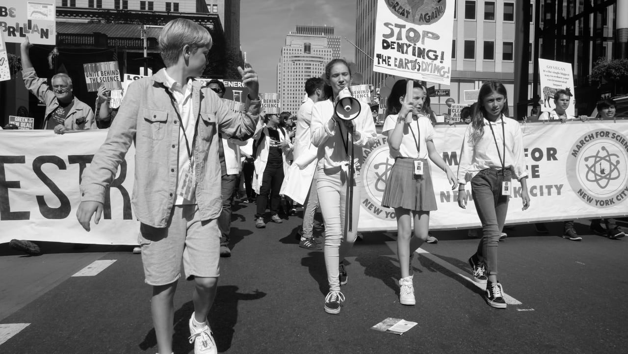 Three young women lead a contingent of scientists in the climate march