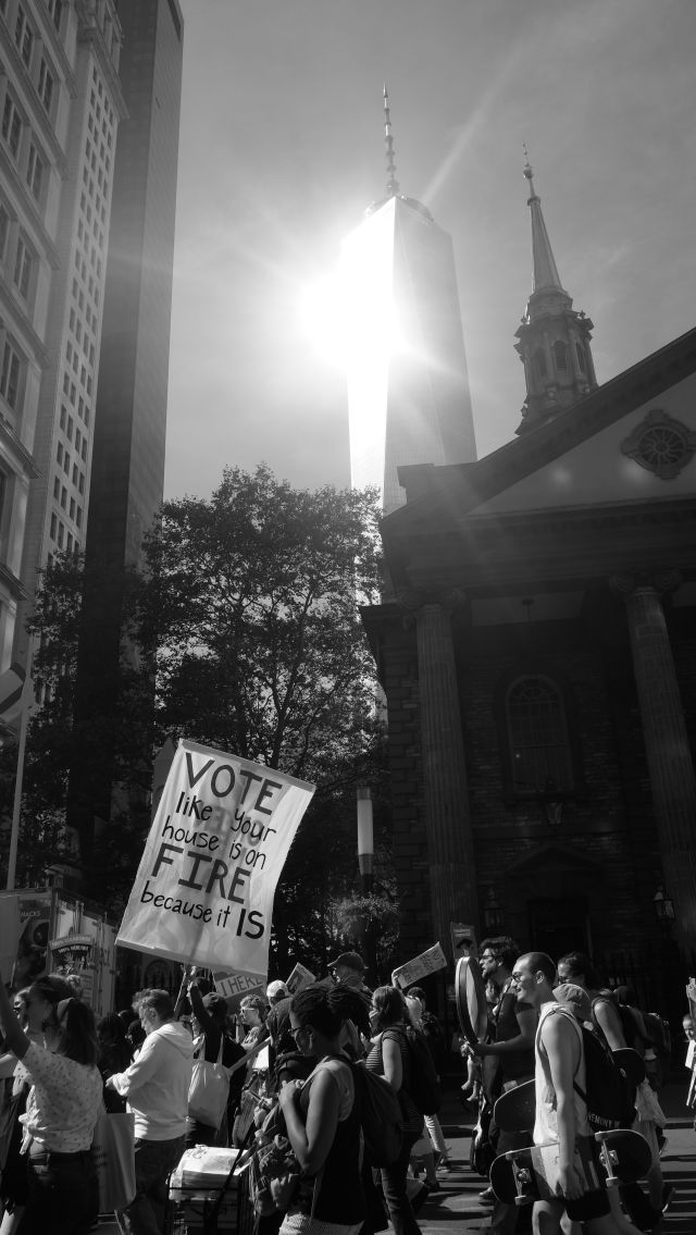 New York’s Climate Strike March passes by as the Freedom Tower shines in the background