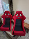 2 Red and Black Fiber Racing Bucket Seat on a Wooden table.