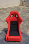 Red and Black Fiber Racing Bucket Seat on a Wooden table.
