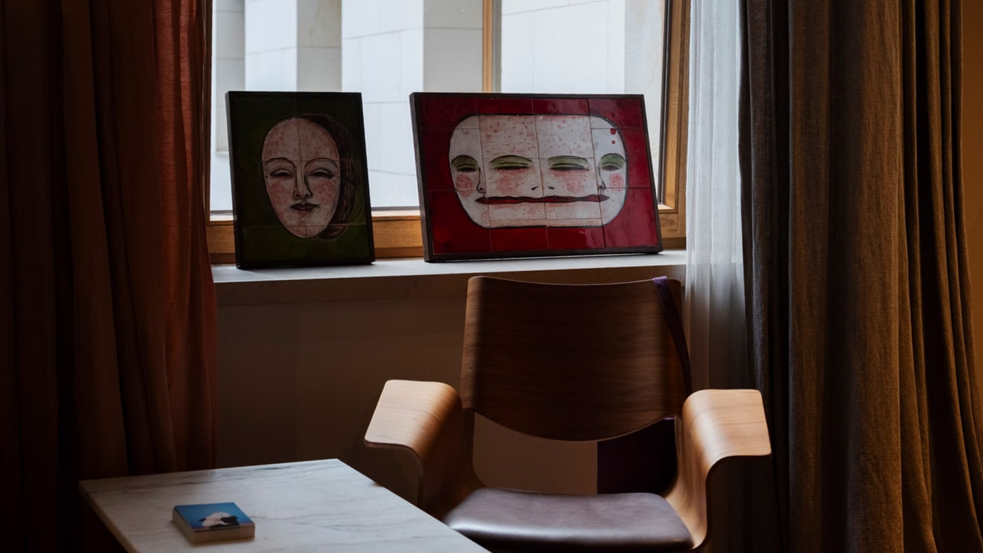 Dois rostos pintados em azulejos expostos junto à janela de um quarto do Hotel Warszawa