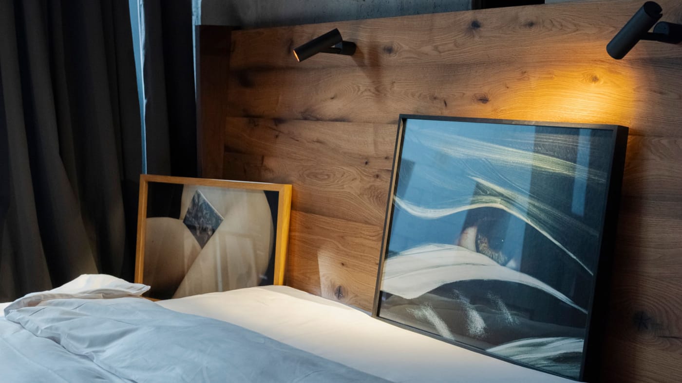 Duas obras emolduradas pousadas na cama de um quarto do Hotel Warszawa durante a Art Fair
