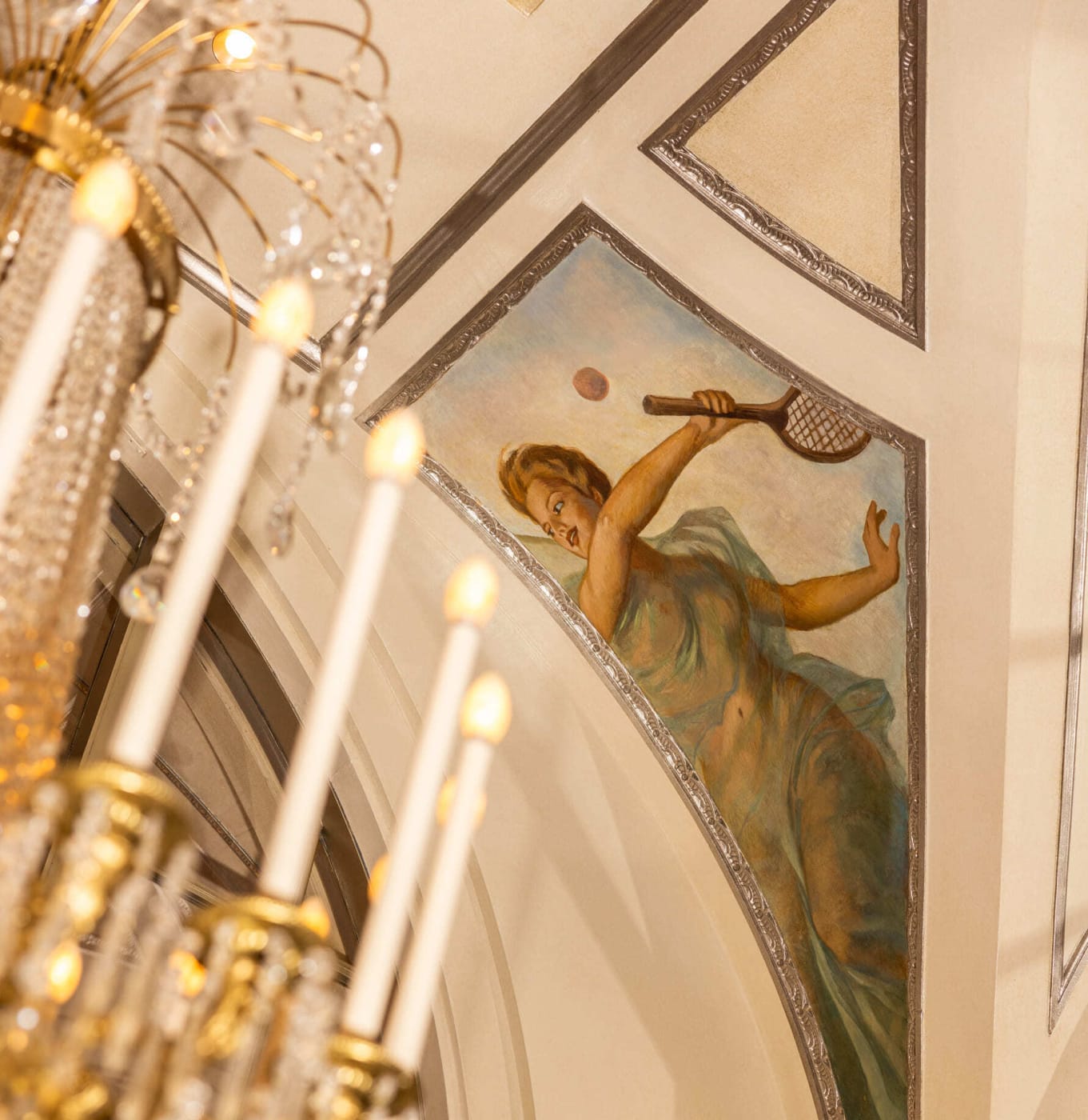 Un fresco de una tenista junto a una lámpara de cristal en el Waldorf Astoria New York