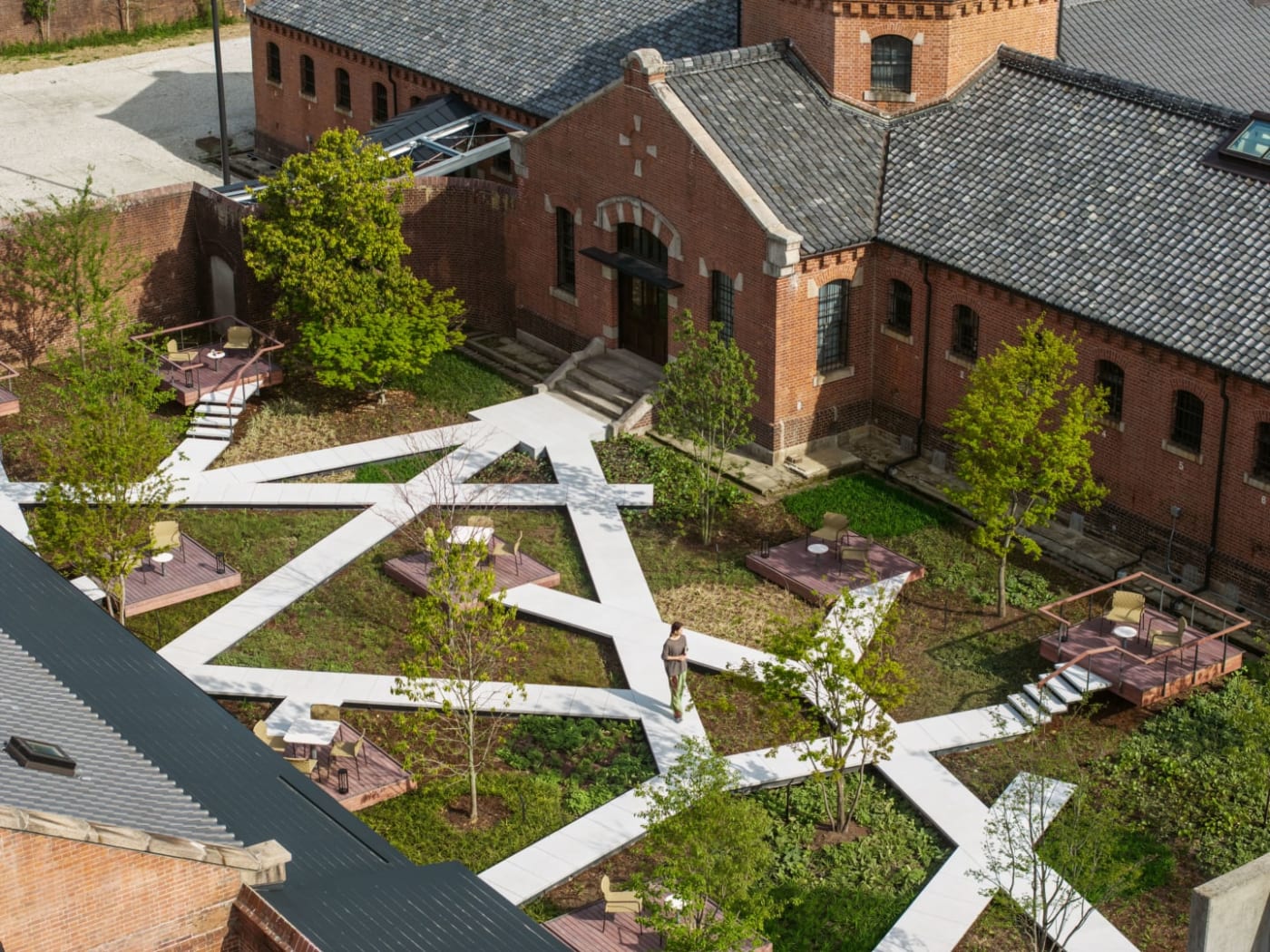 Gestalteter Innenhof mit weißen geometrischen Wegen zwischen den Gebäuden des Hotels Hoshinoya Nara Prison