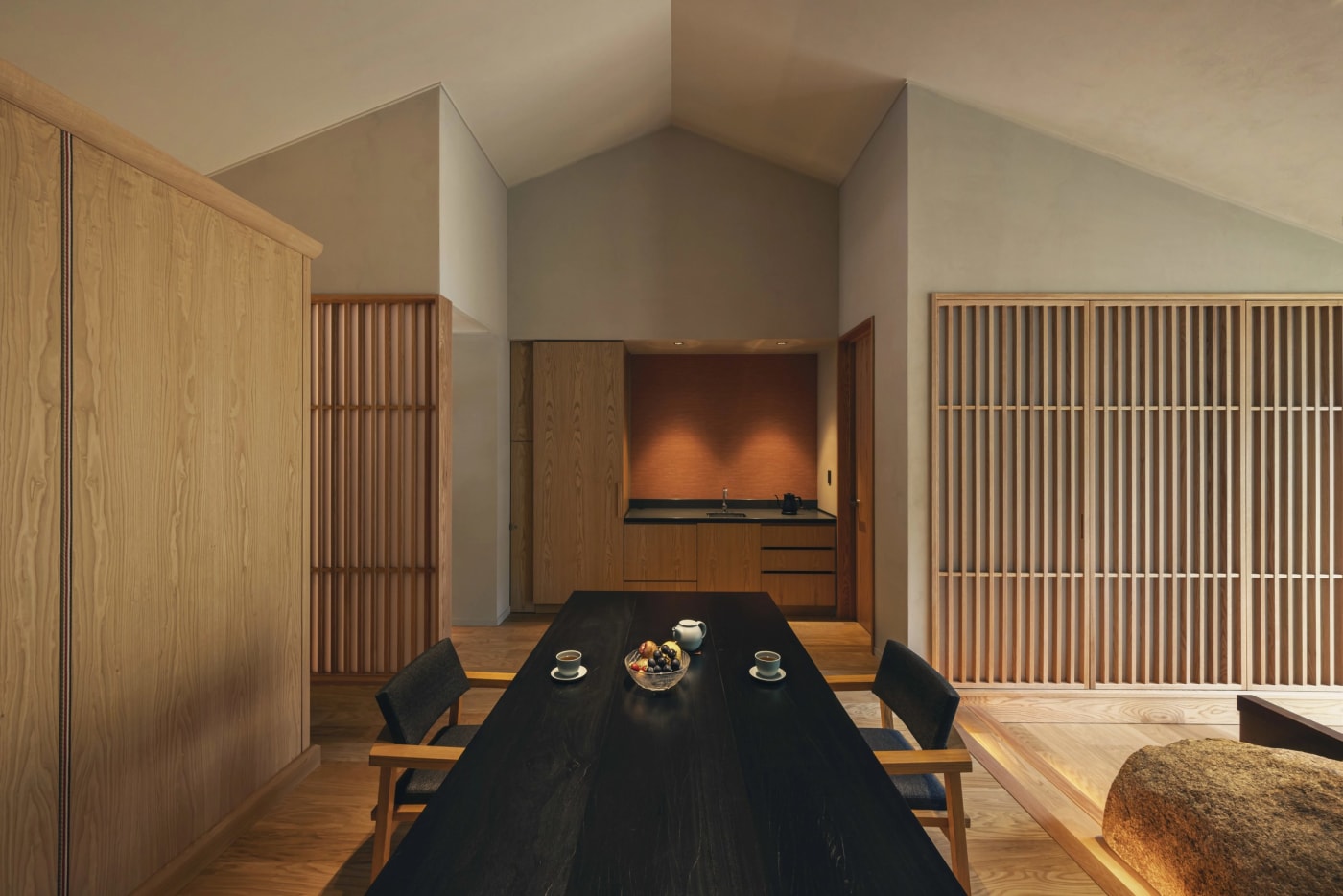 Dining area of a suite at the Hoshinoya Asuka resort under a high sloping ceiling, dark table and lattice screens