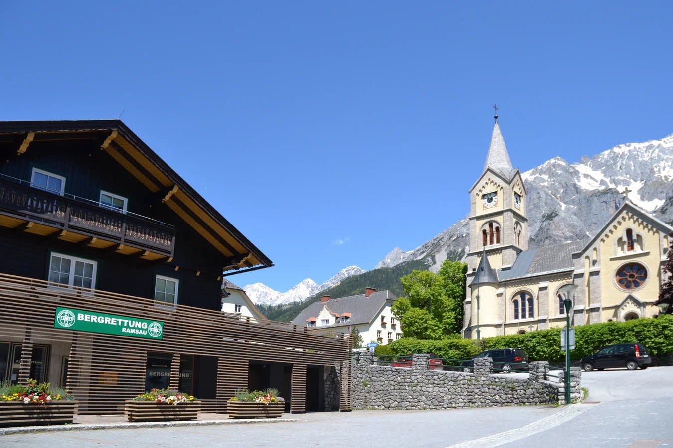 O chalé da Bergretter-Zentrale com a placa Bergrettung, abaixo da igreja protestante de Ramsau am Dachstein