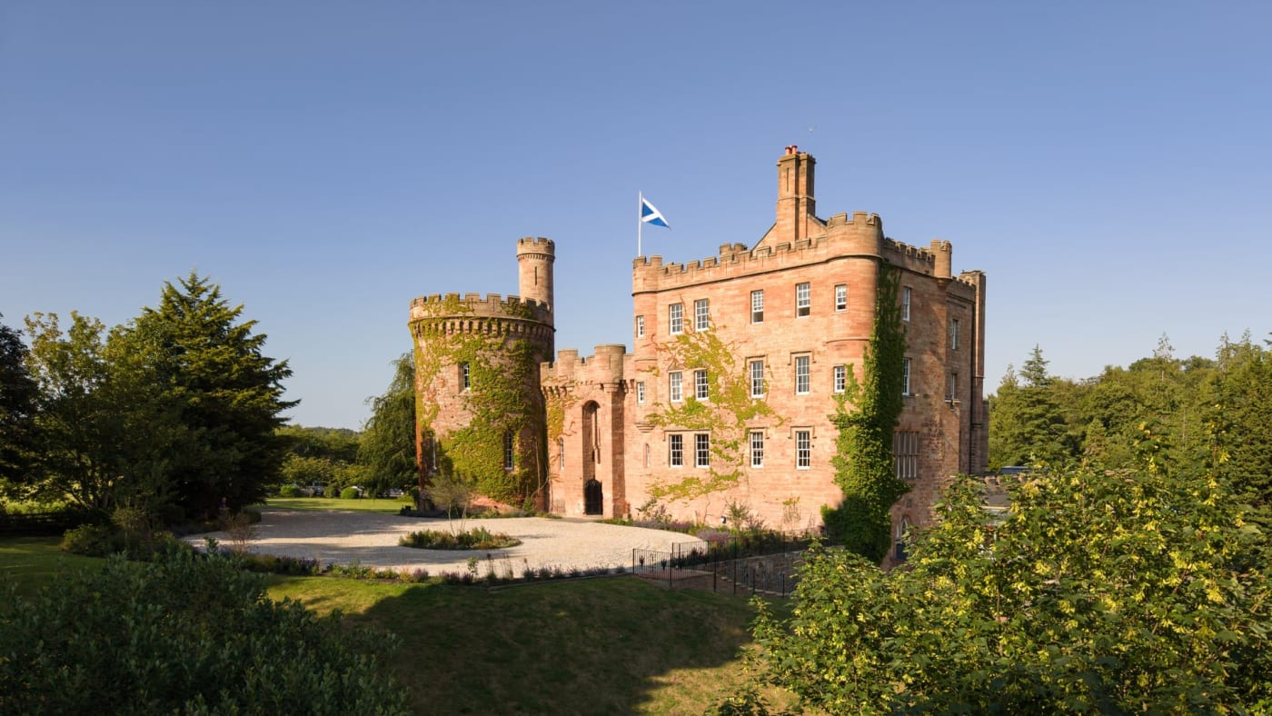 El castillo de Dalhousie, de arenisca roja, con su torre redonda y su bandera escocesa, cerca de Edimburgo