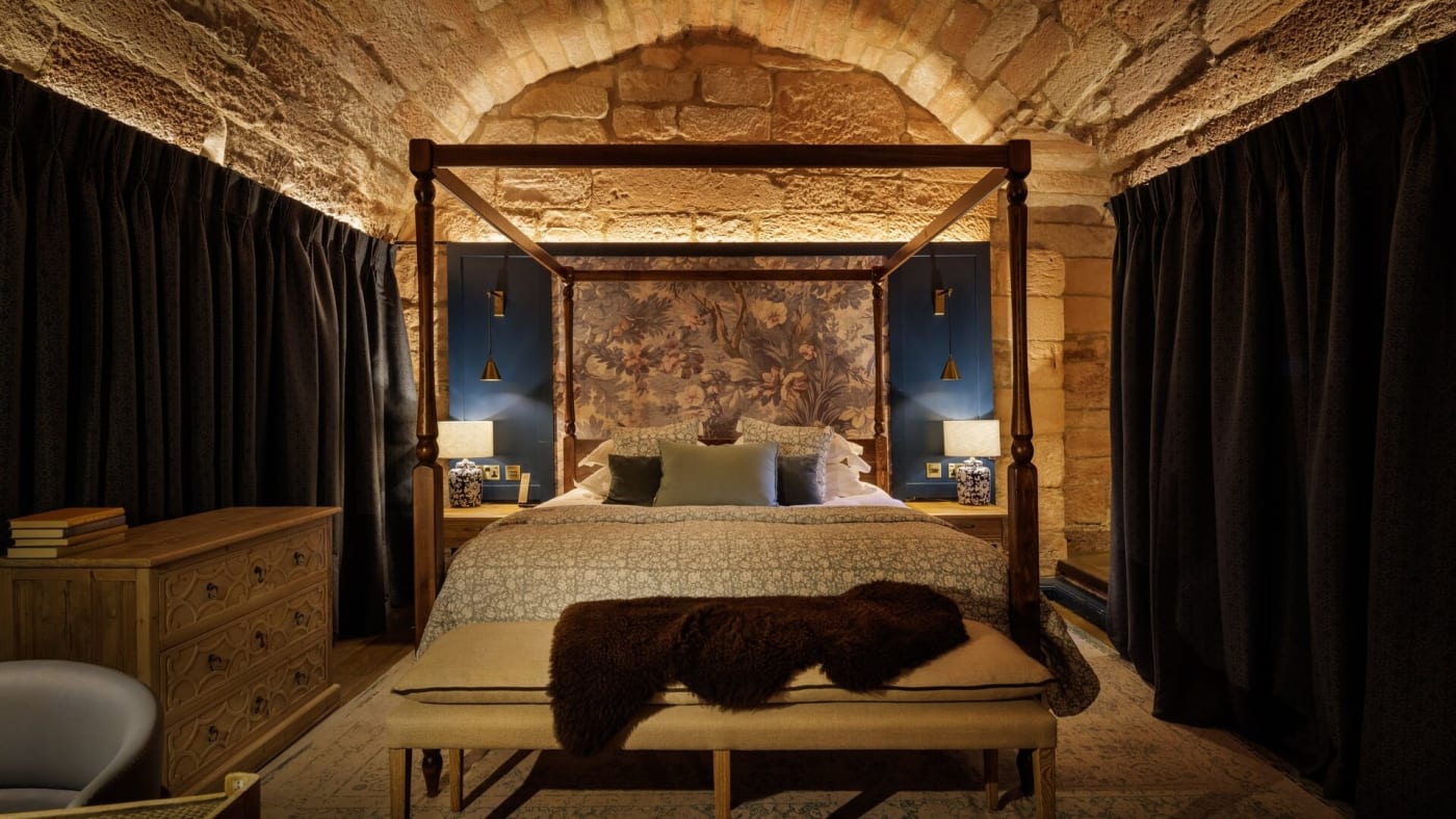 Una habitación abovedada de piedra con cama con dosel, en Dalhousie Castle