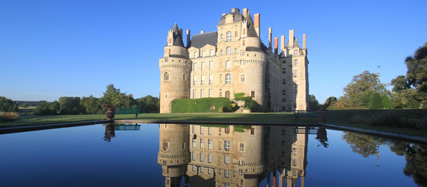 El castillo de Brissac y sus torres reflejados en un estanque, en Anjou