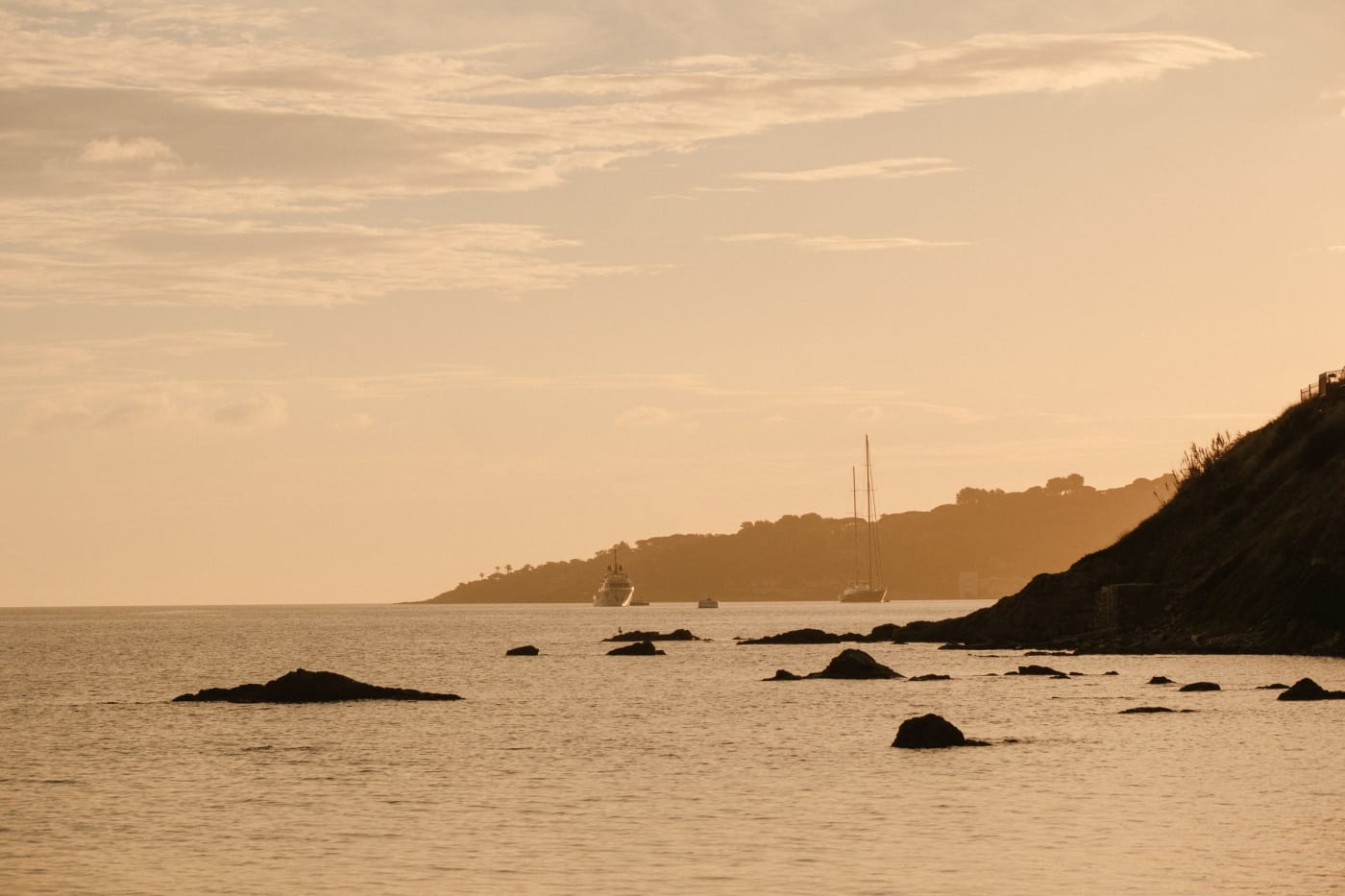 Coucher de soleil doré sur une baie rocheuse et des voiliers au mouillage près de Saint-Tropez