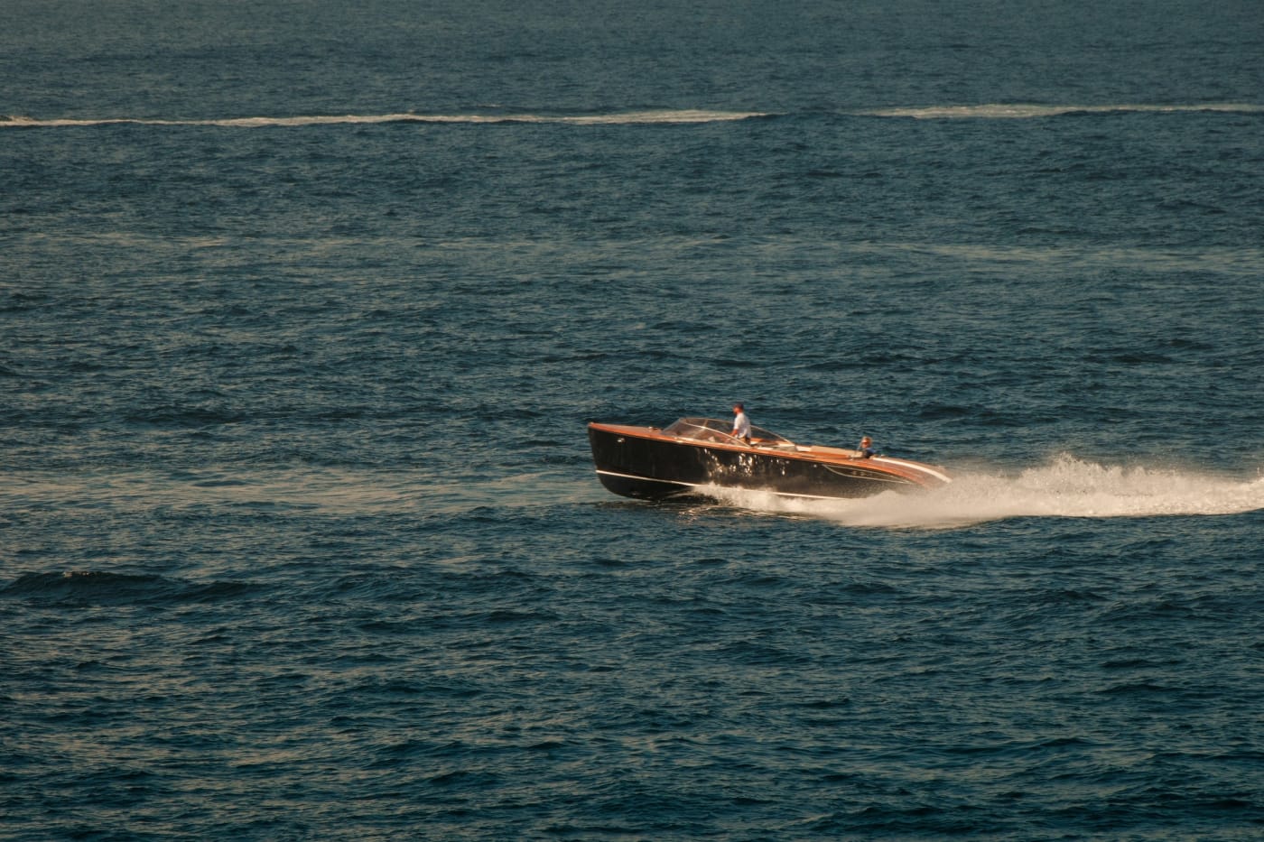 Un bateau runabout en bois verni fend la mer au large de Saint-Tropez