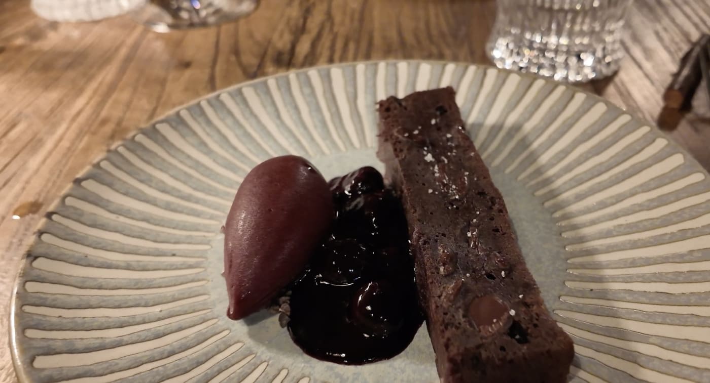 Schokoladen-Brownie, Sorbet und Heidelbeerkompott auf einem gestreiften Teller im Restaurant Ardent des Loire Valley Lodges
