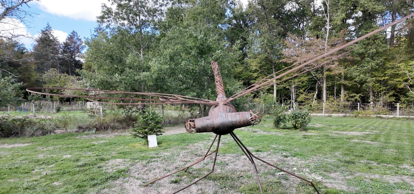 Eine riesige Libellenskulptur aus Metall auf einer Wiese des Loire Valley Lodges am Waldrand