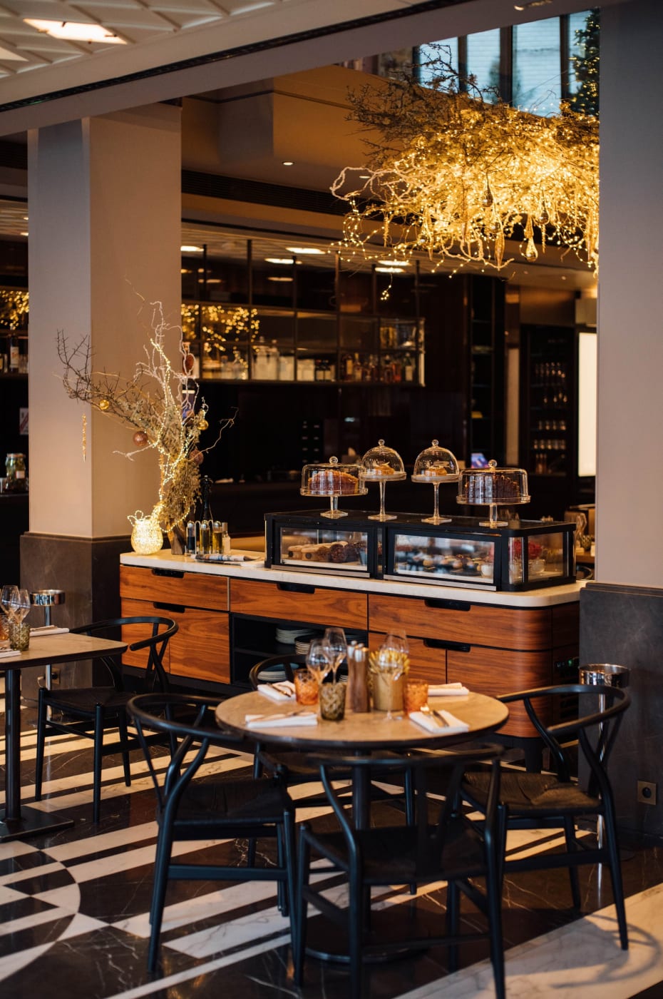 La Brasserie Lutetia del Mandarin Oriental Lutetia en París, mesa redonda y vitrina de postres bajo una lámpara dorada