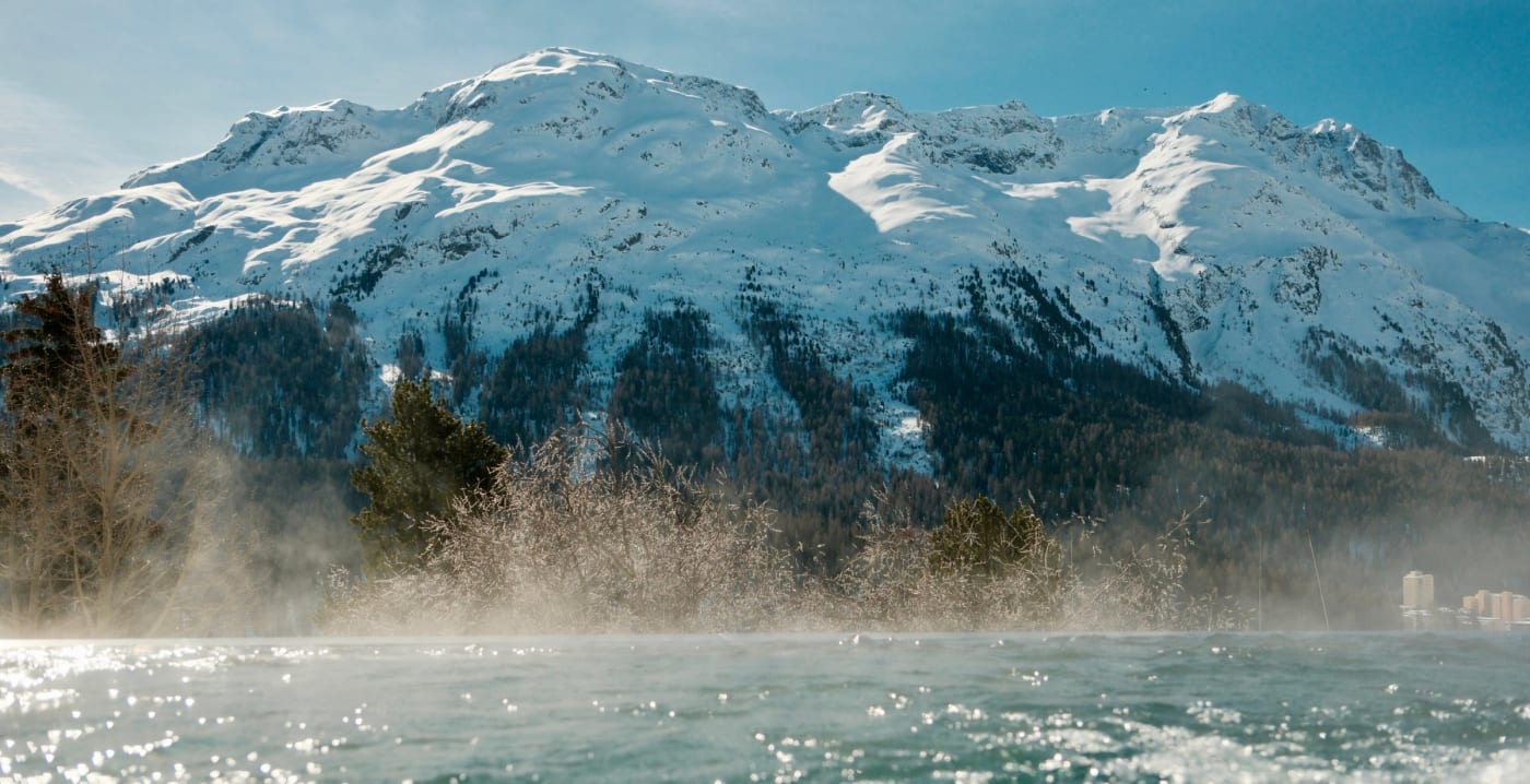 La piscine extérieure fumante du Kulm Hotel St. Moritz face aux sommets enneigés de l'Engadine