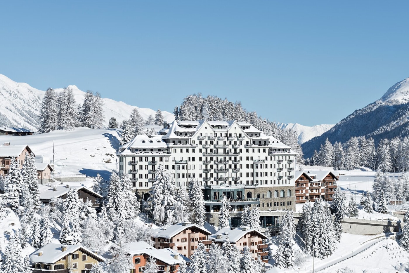 La façade du Carlton Hotel St. Moritz dominant le village enneigé et les sapins