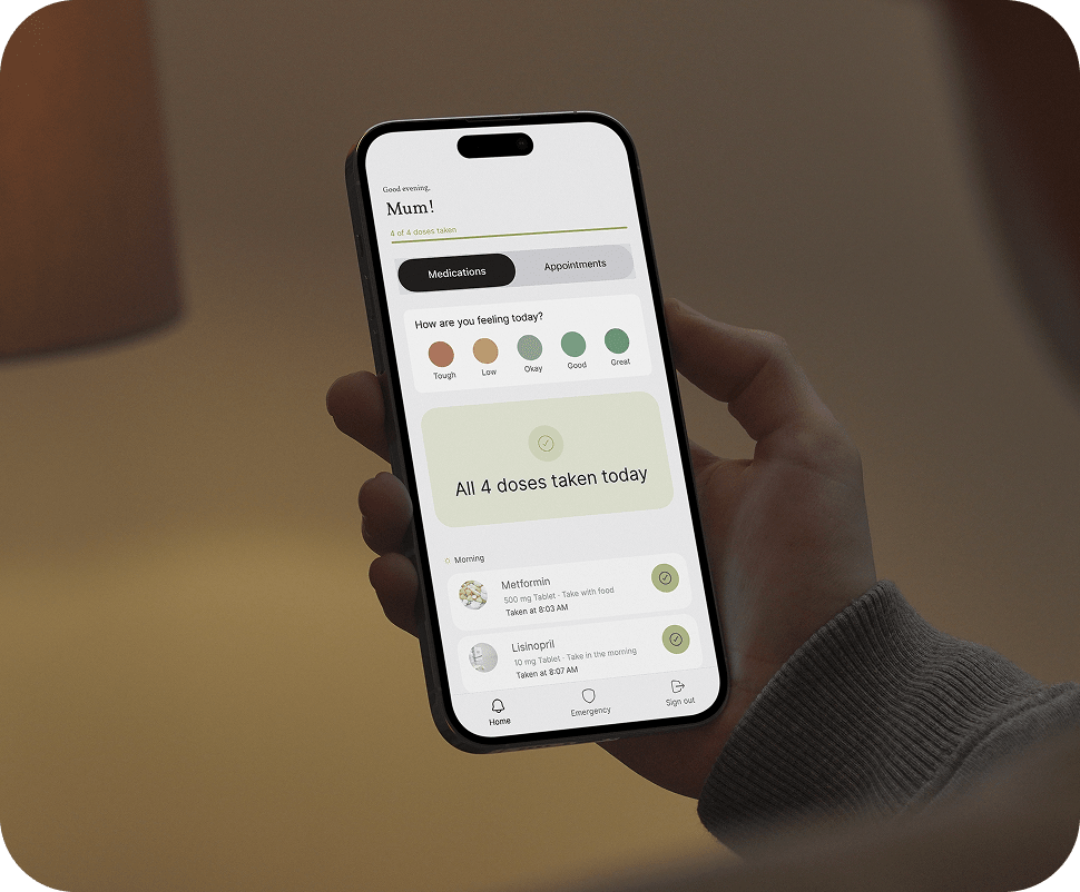 Hand holding an iPhone showing Kinlog parent view for Mum with all doses taken, mood check-in, and morning medications Metformin and Lisinopril marked taken