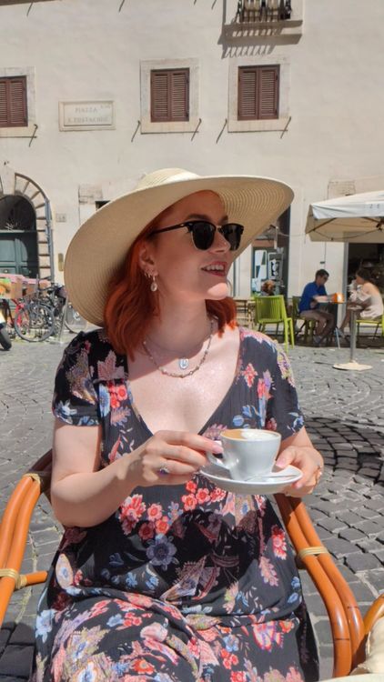 A woman wearing a hat drinking coffee