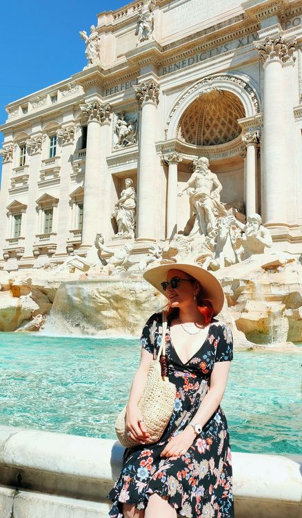 A woman wearing a hat sat next to a water fountain