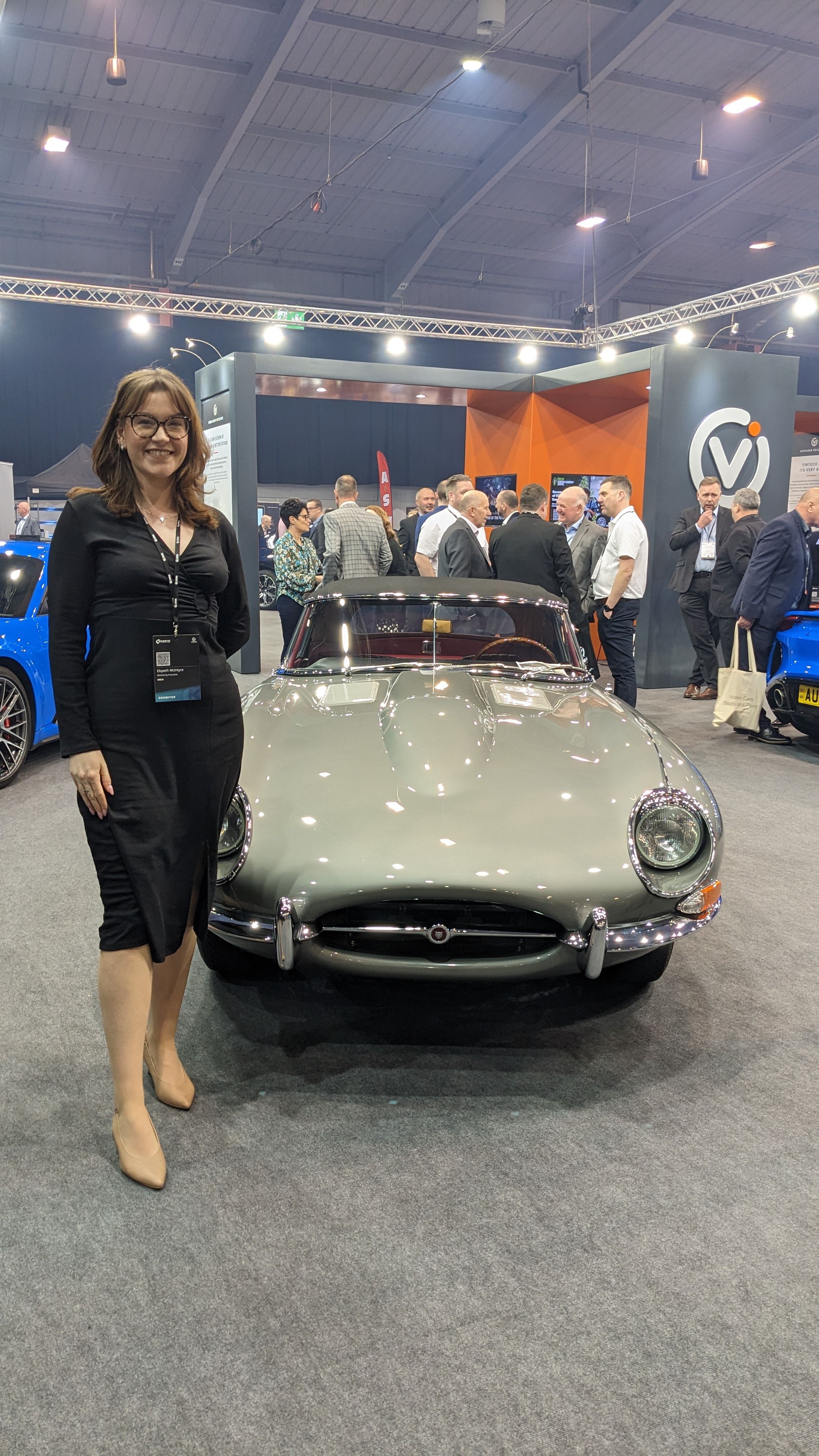 A woman stood in front of an Aston Martin