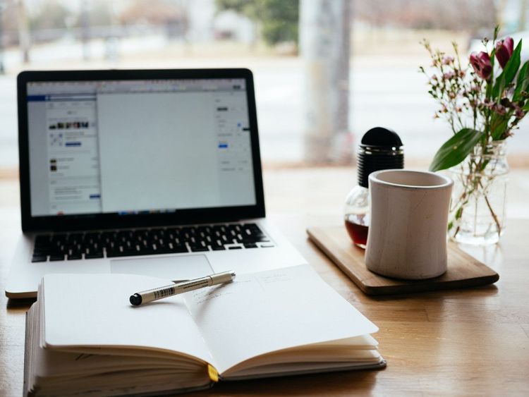 Laptop and notebook on a desk with coffee