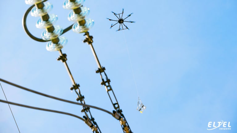 Eine Drohne hängt Vogelschutzmarkierungen vom Typ FireFly an eine unter Spannung stehende 110-kV-Leitung – eltelnetworks.pl