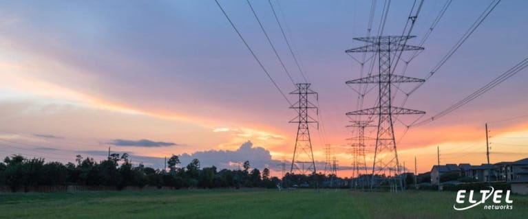Freiluftleitungen, die sich bis zum Horizont erstrecken, daneben eine Wohnsiedlung - eltelnetworks.pl