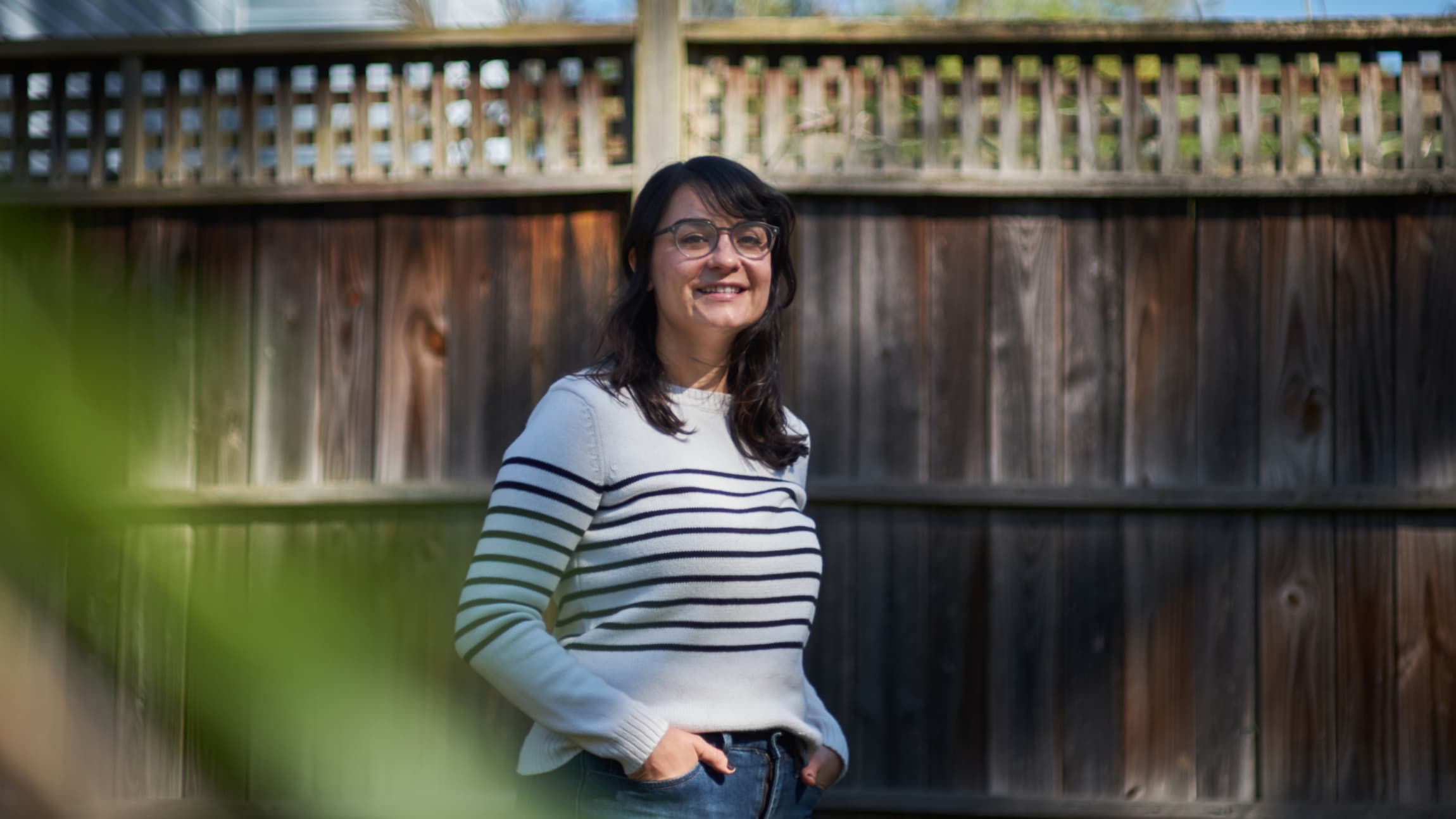 Elyse smiling in front of an old wooden fence