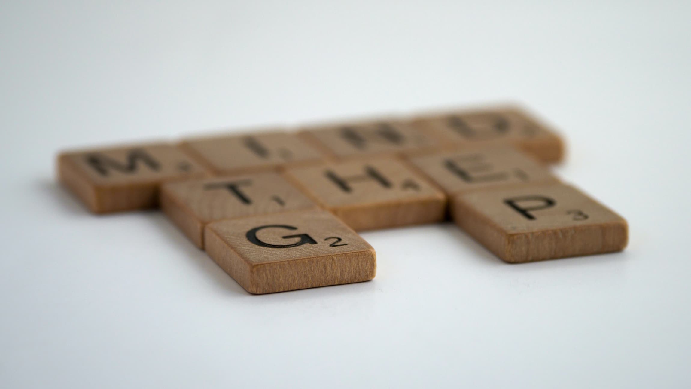 Wooden Scrabble game tiles arranged to spell mind the gap.