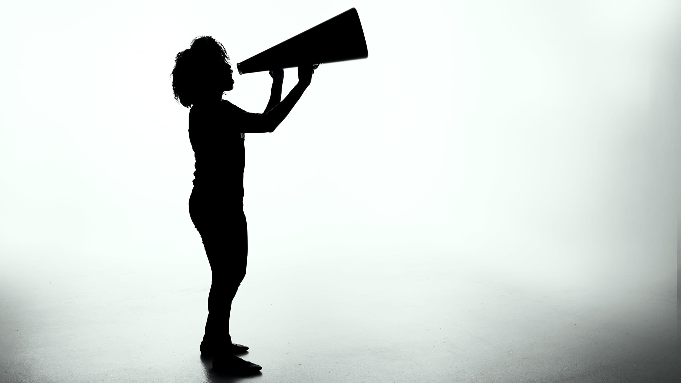 Silhouette of a person yelling into a megaphone. 